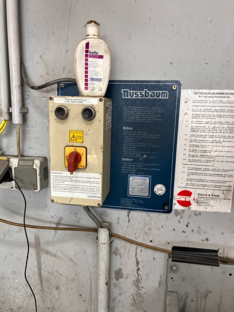 Bedieneinheit einer Nussbaum-Unterflurhebebühne mit Hauptschalter und Bedienungsanleitung